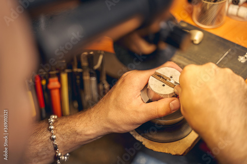 Male jeweler treating a workpiece with a metal tool