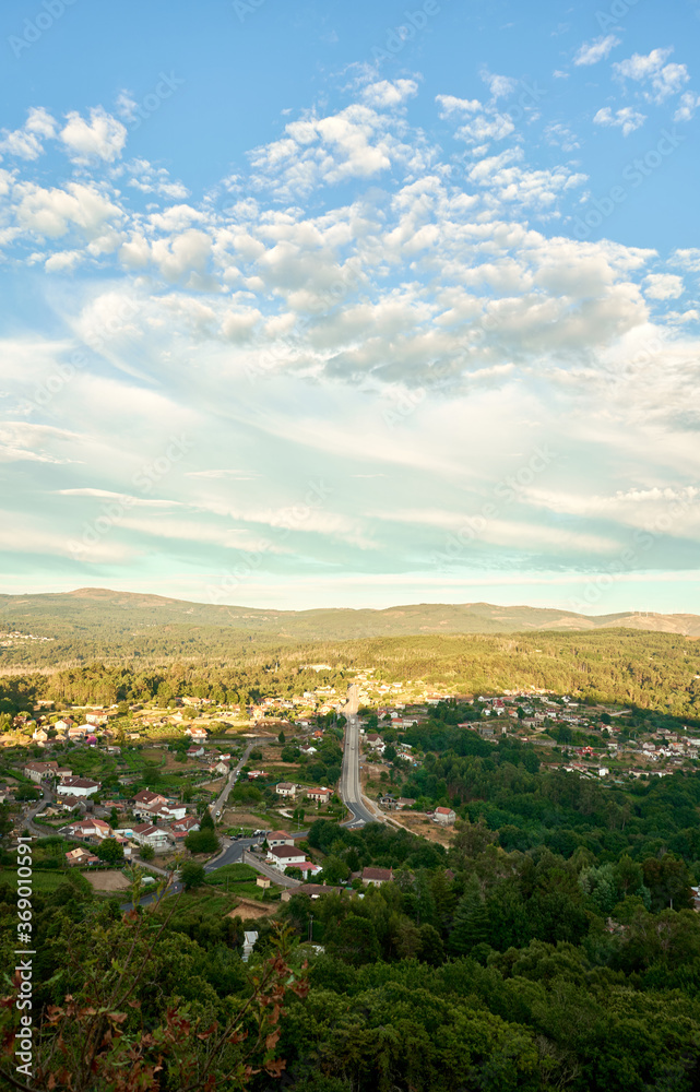 aerial landscape of town surrounded by vegetation with blue sky and clouds in golden hour