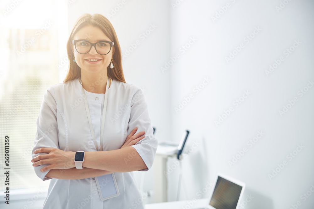 Beautiful happy cosmetologist posing at the photo camera in her office room Beautiful happy cosmetologist posing at the photo camera in her office room