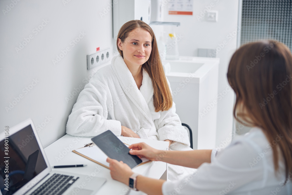 Smiling lady in a white bathrobe sitting on a chair