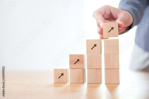 Close up Businessman hand arranging wood cube stacking as step stair. Business concept growth success process.