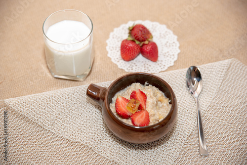 oatmeal porridge with strawberries and a glass of milk