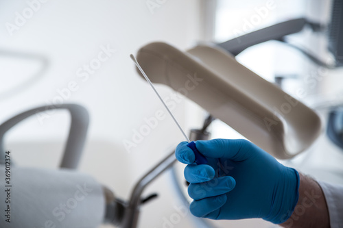 Lekarz w niebieskich rękawiczkach pobiera materiał do cytologii. 