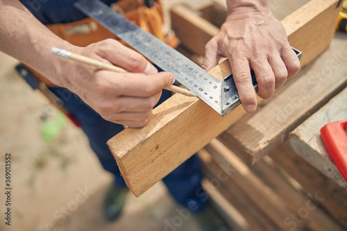 Carpenter measuring the length on one side of the wood