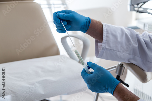 Lekarz w niebieskich rękawiczkach pobiera materiał do cytologii. 