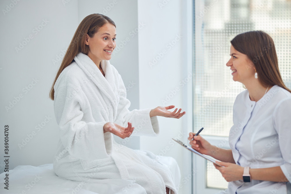 Two smiling women having conversation in the white medicine room Two smiling women having conversation in the white medicine room