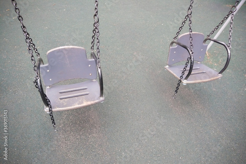 Gray empty teeter on asphalt background, swing made of wood and metal chains. Lonely and abandoned.