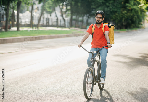 Modern delivery in city. Young man in helmet with bag rides on bicycle