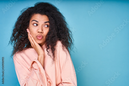 A young sweet dark-skinned lady looks embarrassedly to the side. photo