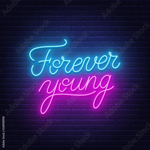 Forever young motivational quote neon lettering on brick wall background.