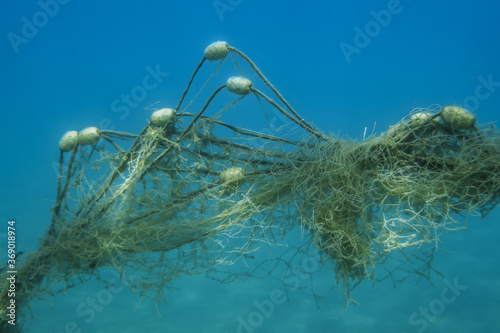 Lost fishing net with buoys lies underwater on the seabed on blue water background. Becici, Budva Municipality, Montenegro