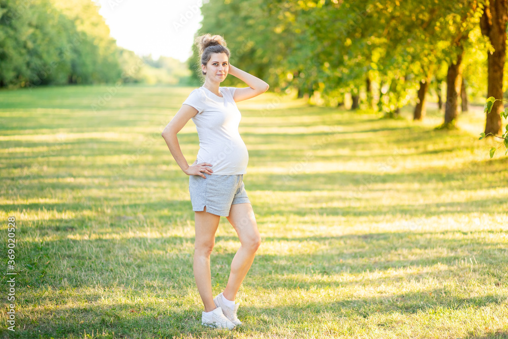 a pregnant girl does sports in nature in the summer, yoga for pregnant women in the fresh air