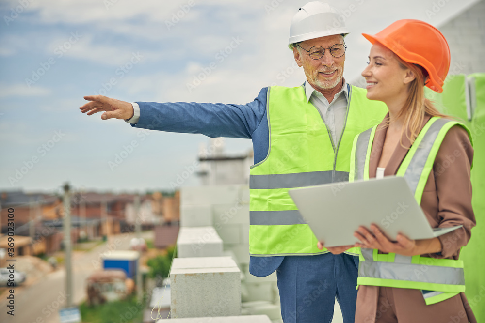 Male worker in eyeglasses showing something to a contractor Male worker in eyeglasses showing something to a contractor