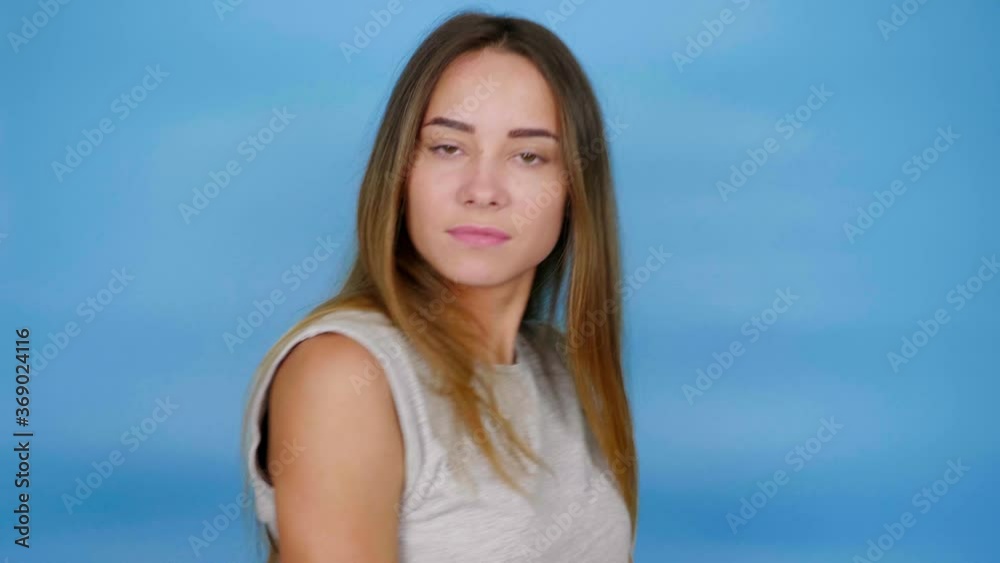 Beautiful woman with long hair in gray t-shirt is dancing on blue background with copy space. 4K slow motion footage Beautiful woman with long hair in gray t-shirt is dancing on blue background with copy space. 4K slow motion footage
