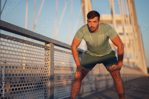 Young man is exercising outdoor on bridge in the city.