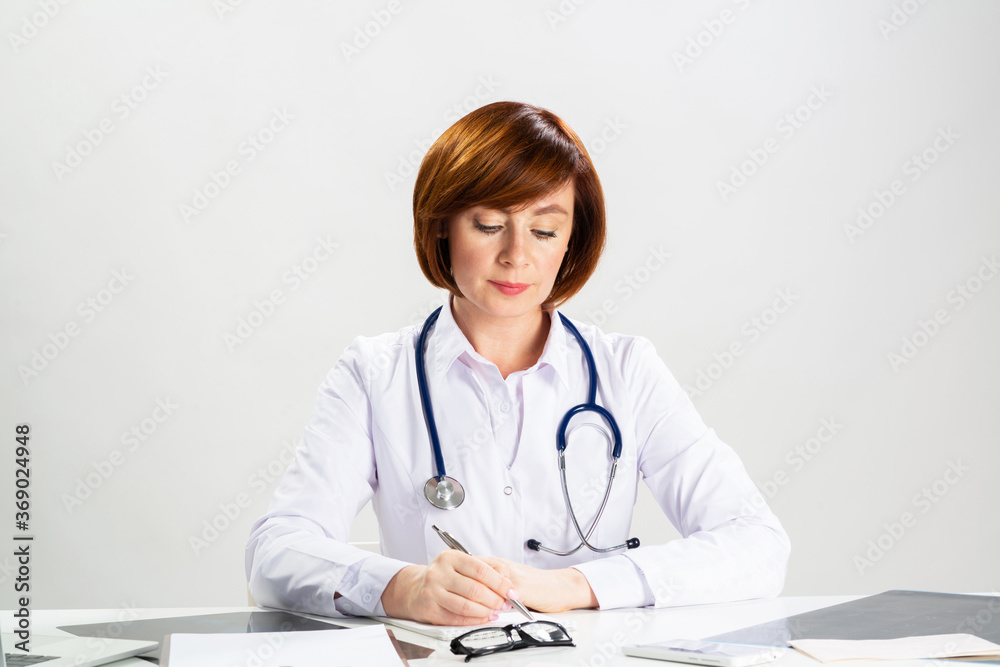 Beautiful doctor sitting in office and writing Beautiful doctor sitting in office and writing