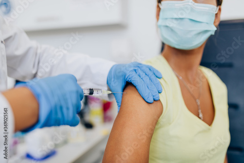 Female doctor or nurse giving shot or vaccine to a patient s shoulder. Vaccination and prevention against flu or virus pandemic.