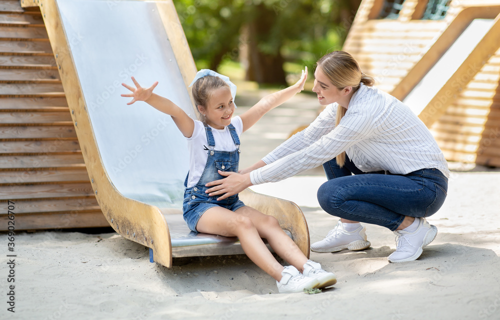 Kid Girl Riding Down The Slide On Playground With Mom Kid Girl Riding Down The Slide On Playground With Mom