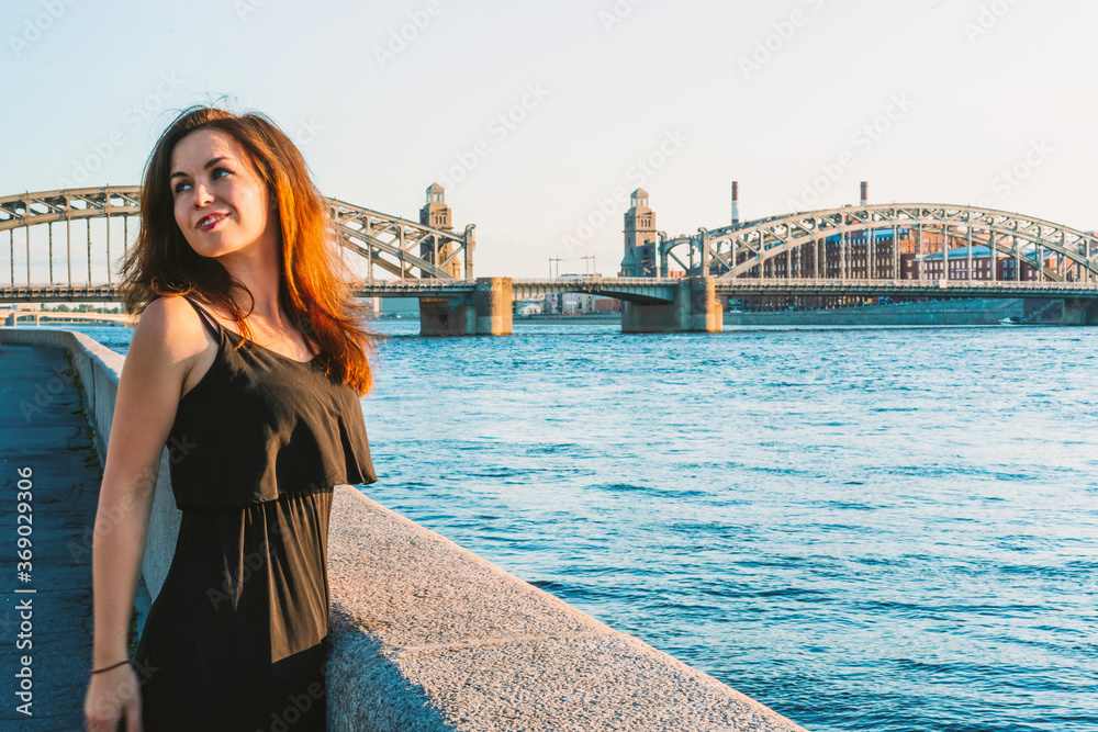 A young woman on the background of Bolsheokhtinsky bridge in Saint Petersburg in the summer