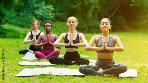 Peaceful diverse girls meditating during their outdoor yoga practice in morning