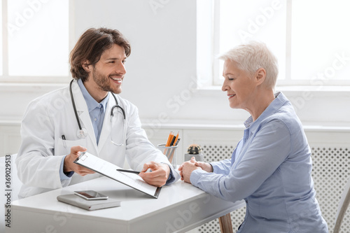 Cheerful doctor showing good test results to senior patient
