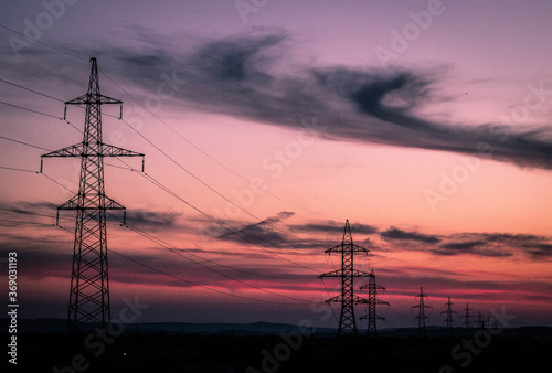 High voltage poles stand against the sunset