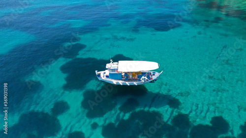 Aerial drone photo of beautiful fishing boat anchored in turquoise sea of Stafilos bay, Skopelos island, Sporades, Greece