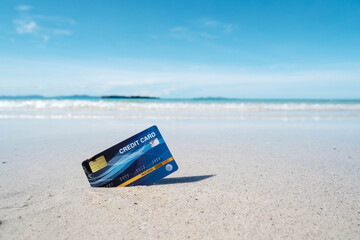 A blue credit card placed on a tropical beach
