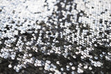 Sequin fabric texture. Shiny silver sparkling background. Clothing piece of glitter metallic for a glamorous party, celebration. Close-up.