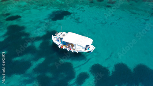 Aerial drone photo of beautiful fishing boat anchored in turquoise sea of Stafilos bay, Skopelos island, Sporades, Greece © aerial-drone