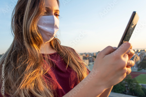 Woman wearing mask texting outdoors