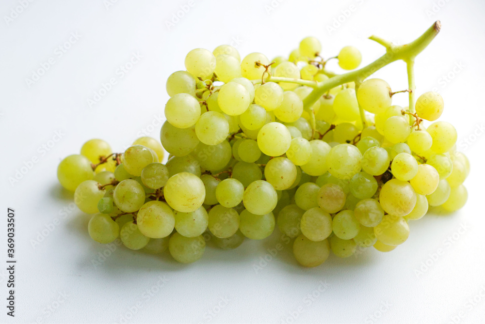 a bunch of green kish-mish grapes lies on a light surface. Natural fruit dessert. A tasty, healthy snack, a slice of summer, a harvest. Imported grapes. Bunch of amber grapes