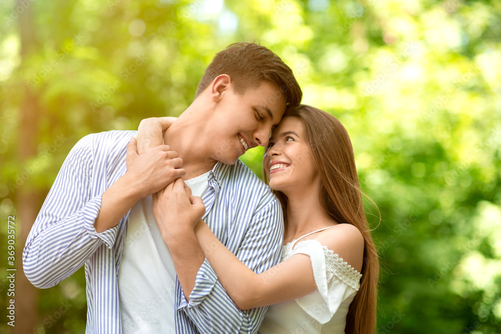 Portrait of affectionate couple hugging at park on sunny summer day Portrait of affectionate couple hugging at park on sunny summer day