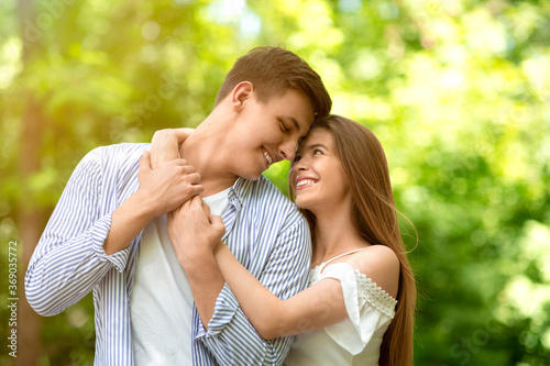 Portrait of affectionate couple hugging at park on sunny summer day