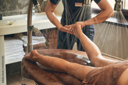Woman legs on the wooden table under shower rain in spa beauty center photo