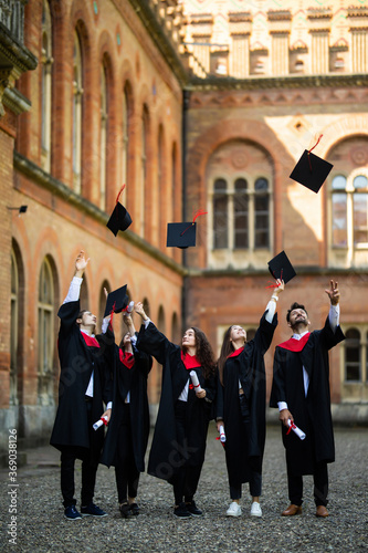 education, graduation and people concept. Group of happy international students in bachelor gowns throwing mortar boards up