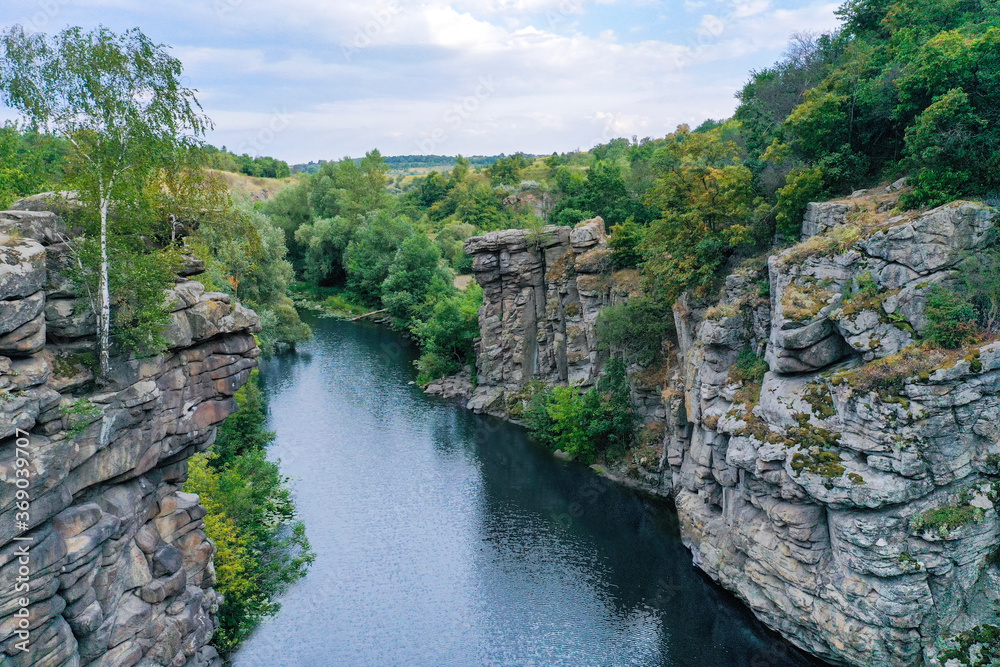 Naklejka premium large stone rocks with a river between them with clear water. Trees grow on the rocks.