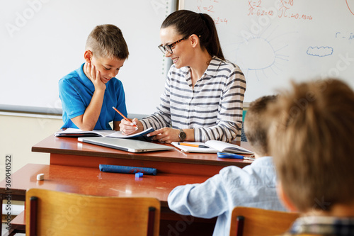 Female teacher helps her student to resolve mathematics assignment .