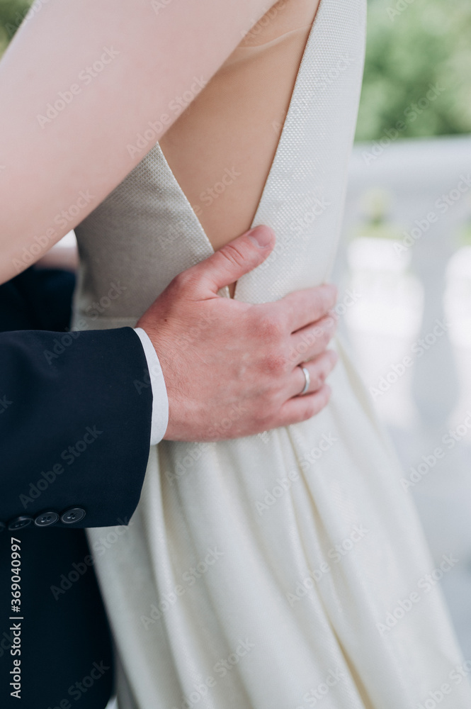 the groom holds the bride by the waist with his hands
