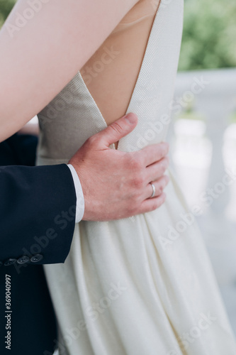the groom holds the bride by the waist with his hands