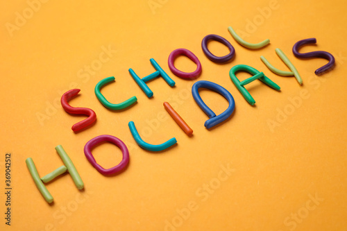 Phrase School Holidays made of modeling clay on orange background