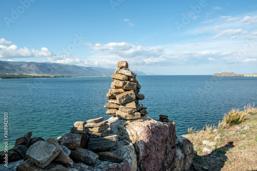 Pile of stones built in cairn on the background of lake Baikal. Calmness and detachment with nature