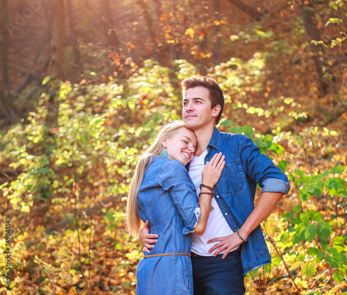 Young couple in love together in happy embrace in autumn forest, in rays of setting sun © okostia