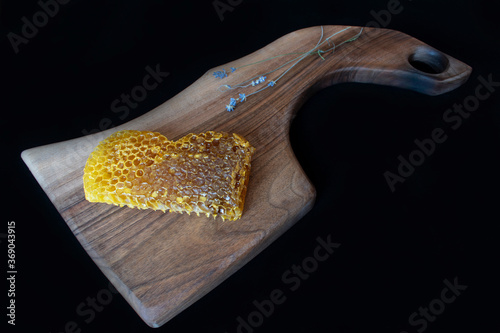 Raw honeycomb on cutting board. Black background,copy space, natural product