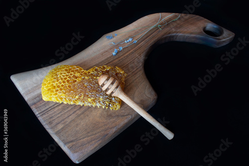 Raw honeycomb on cutting board. Black background,copy space, natural product