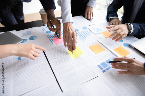 Close up table full of papers, diverse businesspeople analyzing report in charts and graphs discuss paperwork data statistics at group meeting. Research overview activity, brainstorm teamwork concept photo