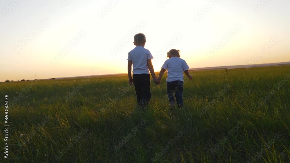 Children boy and girl walking on the green grass holding hands. Children boy and girl walking on the green grass holding hands.