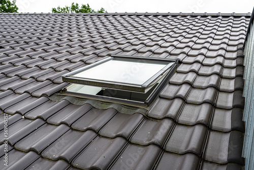 Tableau sur toile One open roof window in the attic, visible anthracite ceramic tiles