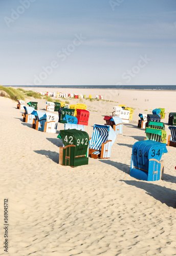 Colorful beach chairs in white sand in the morning on the Frisian island of Juist.