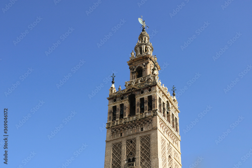the top of Giralda tower in Seville isolated with a clean blue sky in the background for a wallpaper